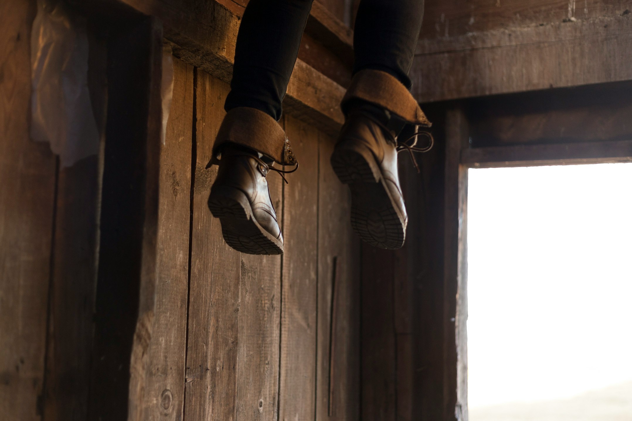 person feet with brown leather boots dangling by the entrance